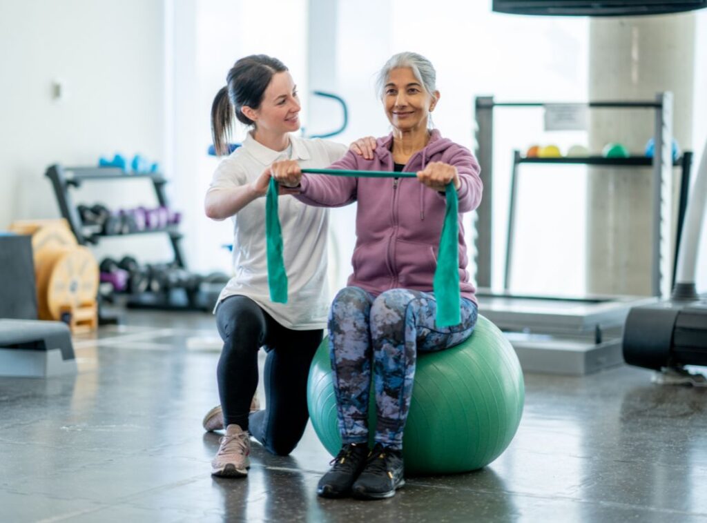Therapist supporting an older adult during a resistance-band exercise